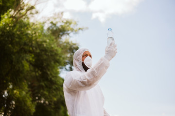 A biologist in protective equipment, with a mask on his face, checks the quality of the water from...