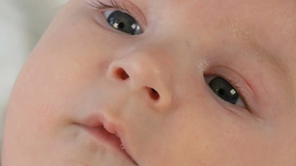 Portrait of beautiful funny little newborn baby of two months lying on a white bed
