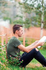 Happy young urban man with book outdoors