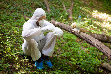 A biologist takes a sample of water from a forest stream