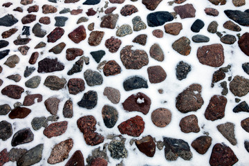 Texture of cobblestone pavement after snowfall.