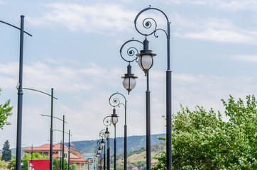 beautiful street lights, standing in a row and creating a rhythm against the sky with clouds