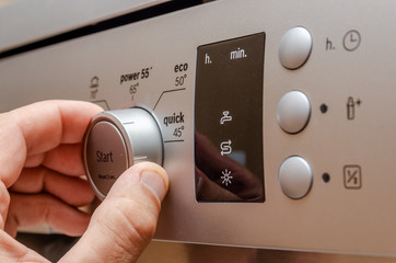 man's hand sets in stylish gray dishwasher control panel