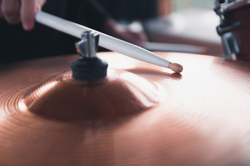 Obraz na płótnie Canvas Close-up of a drummer's hand holding white drum sticks while sitting behind a drum set.