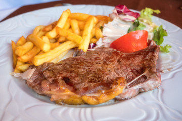 Roasted veal steak with fried potato (french fries) and salad on the white plate, served meat dish
