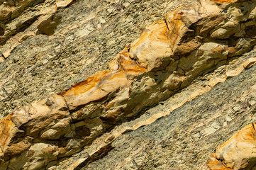 Seamless stone texture with fragments of yellow and orange rocks as original background. Striped textured backdrop from really nature