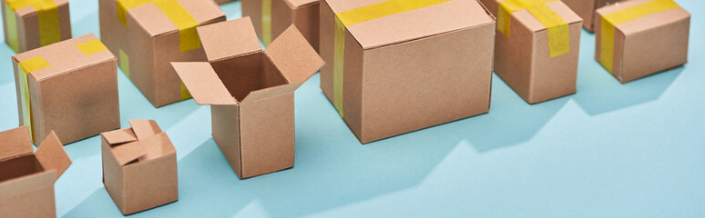 panoramic shot of carton postal boxes on blue background