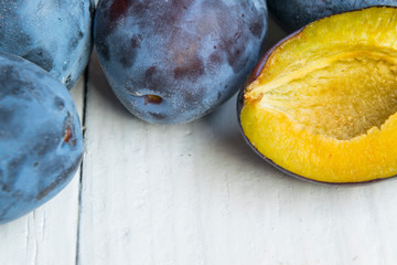 Close up photo of fresh and ripped plums on wooden table