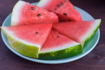 fresh sliced watermelon on a plate, wooden background
