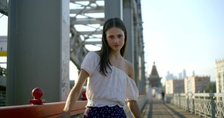 sensual young woman is walking back on road on railway bridge in city in summer
