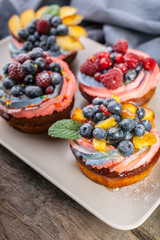 Delicious berry desserts with various berries: red and black currants, blueberries, raspberries, peaches with almonds. Vertical shot