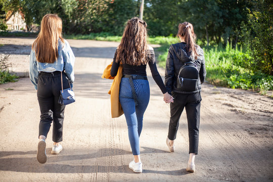 Teenage girls are walking on the street. Three friends dressed fashionably and went looking for the guys. Youth with a sense of style.