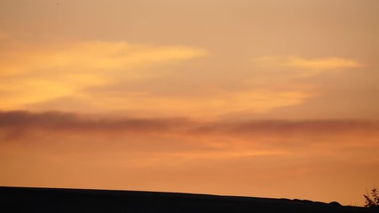 Nice natural colours of sunset sky, warm summer evening hour. Stretched clouds illuminated by hidden sun, orange and yellow shades softly change