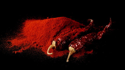 Dry red spicy peppers and powder isolated on black background
