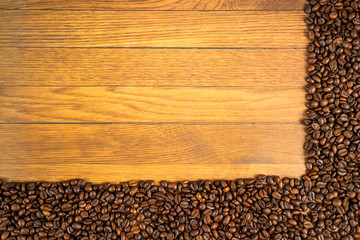 Coffee beans frame with beans at the bottom and right side on a oak background