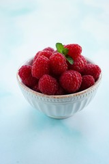 Fresh Raspberries in a bowl on blue background, selective focus