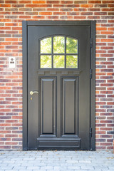 black wooden entrance door in a brick wall