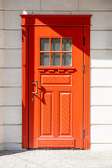 red wooden front door in a white stone wall