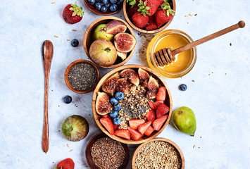 Healthy breakfast and breakfast ingredients, oatmeal with fruits and berries, figs, blueberries, strawberries, flax and chia seeds, honey. Top view, flat lay