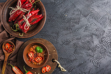 Spicy chili on a dark background in ceramic plates, flatlay.