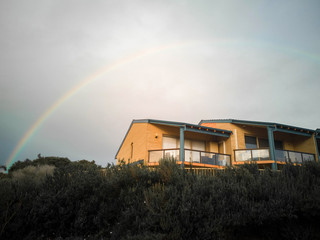 full rainbow over the house with grass in front 
