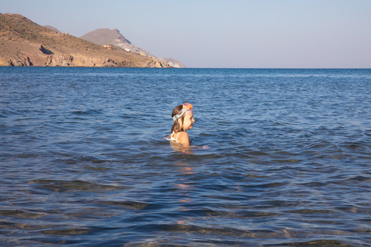 little girl with diving glasses on the head in the water of Genoveses Beach, in Cabo de Gata Natural Park, famous and touristic destination, in Almeria (Andalusia, Spain)