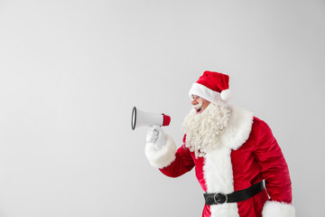 Portrait of Santa Claus with megaphone on light background
