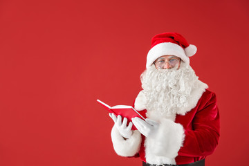 Portrait of Santa Claus with book on color background