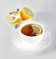 Cup of hot tea with lemon and lavender on white background