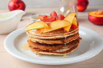 Tasty pancakes with honey and peach on wooden table