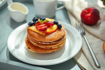 Plate with tasty pancakes on table