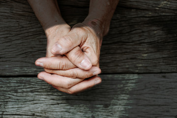 praying hand of old woman on wooden desk background