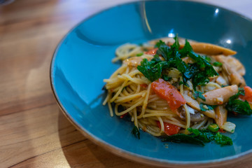 Spicy Sausage Spaghetti in blue plate on wooden background