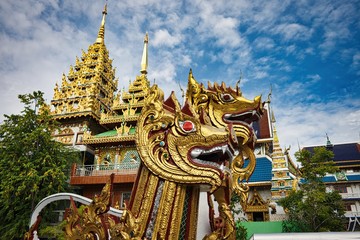 Fototapeta na wymiar タイのお寺イメージ　ど派手なゴールデン狛犬　とド派手な寺　青空と雲がいい感じ