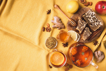 Fototapeta na wymiar Ingredients for healthy hot drink. Lemon, calendula, ginger, mint, honey, apple and spices over yellow background. Copy space. Top view. Alternative medicine concept. Clean eating, detox