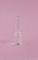 Glass medical ampoules on a pink background.