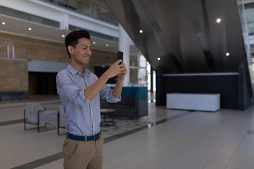 Asian male executive taking selfie with mobile phone in the lobby