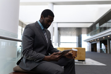 Fototapeta premium African-American businessman with coffee cup using digital tablet in office