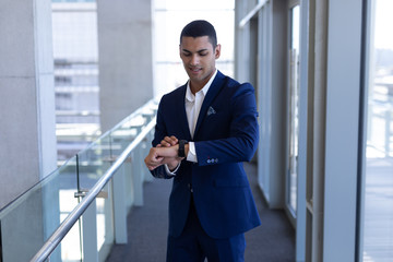 Fototapeta premium Mixed-race businessman using smartwatch in modern office 