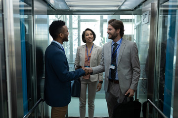 Multi-ethnic usiness colleague interacting with each other in the elevator.