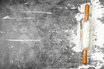 Rolling pin and white flour on a gray background. Bake menu, recipe, homemade pastry concept. Free space for text . Flat lay, top view, copy space for your text.