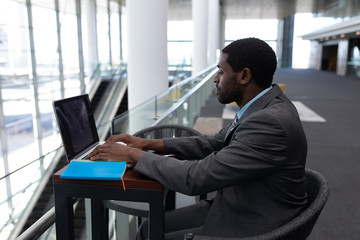 Caucasian businessman sitting at table and working on laptop in modern office