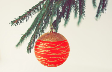 one red gold colors Christmas ball on a Christmas tree branch on white background. Minimal Xmas concept. copy space