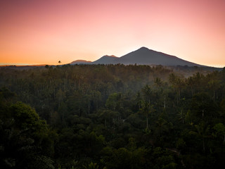 Obraz premium Mount Agung volcano surrounded by dense rainforest with a dramatic sunrise, Bali, Indonesia
