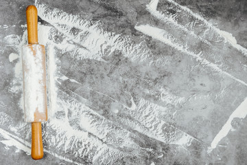 Rolling pin and white flour on a gray background. Bake menu, recipe, homemade pastry concept. Free space for text . Flat lay, top view, copy space for your text.