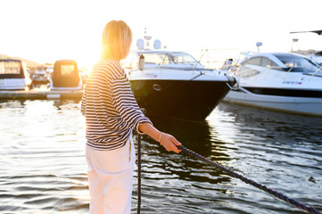 girl sailor pulls the marine rope to the yacht moored. Sea style clothes