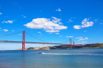 view of bridge in Lisbon and motorboat on the Tagus river 
