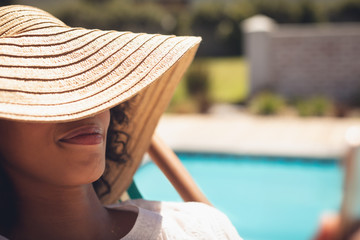 African American woman with hat relaxing on sun lounger in her backyard