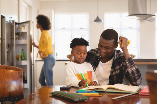 African American father helping his son with homework at table