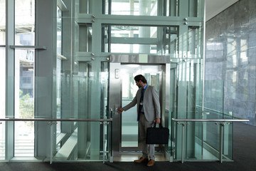 Caucasian businessman getting in the modern elevator at office